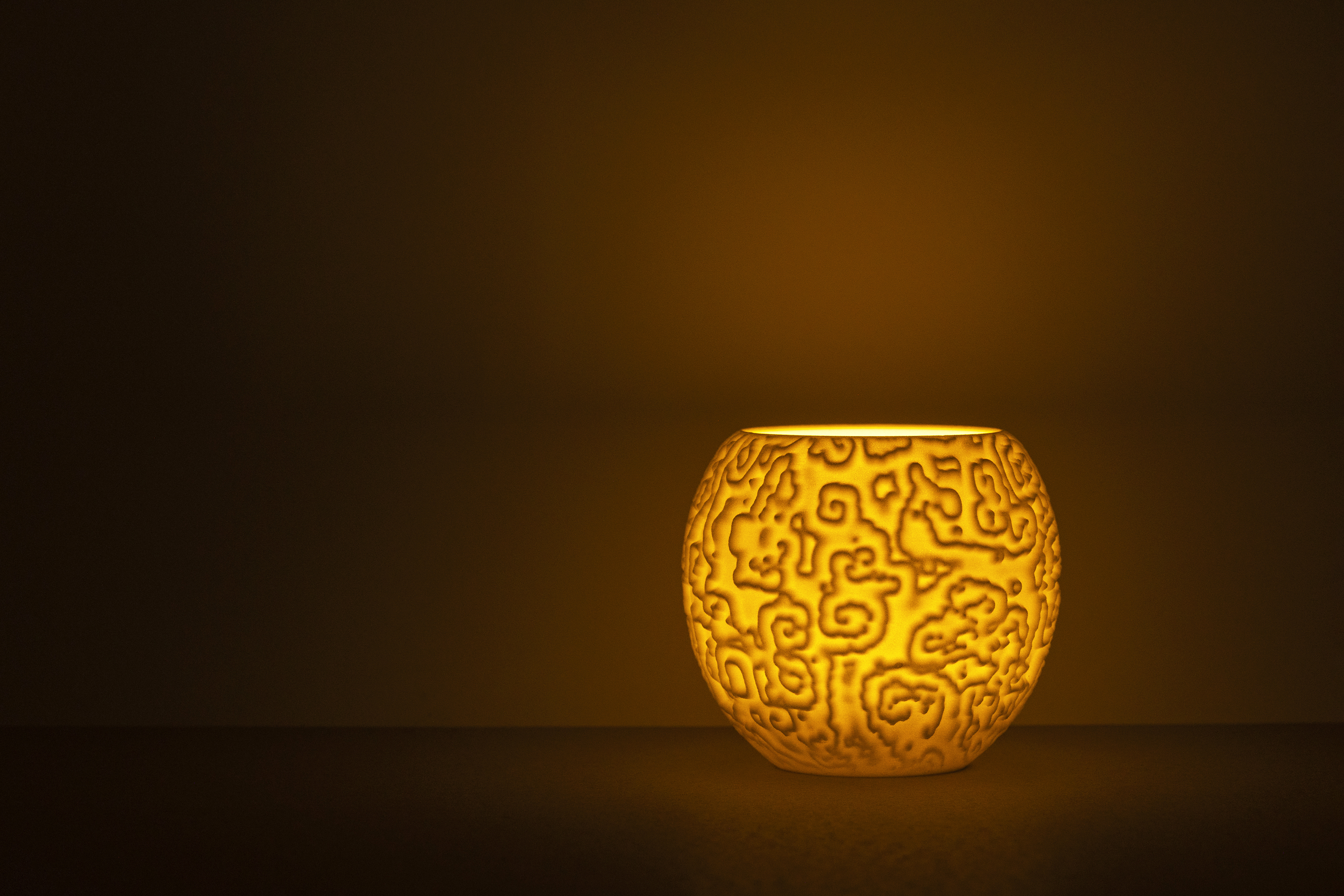 Decorative suggestion for Alluvial Crush: Tealight holder featuring intricate glyphs from reaction-diffusion simulation. Adds a visual symphony of mesmerizing patterns - variant Original (Elegant white), an original product by Cosmic Jubilee (1 of 3) - presented as a tealight, switched on.