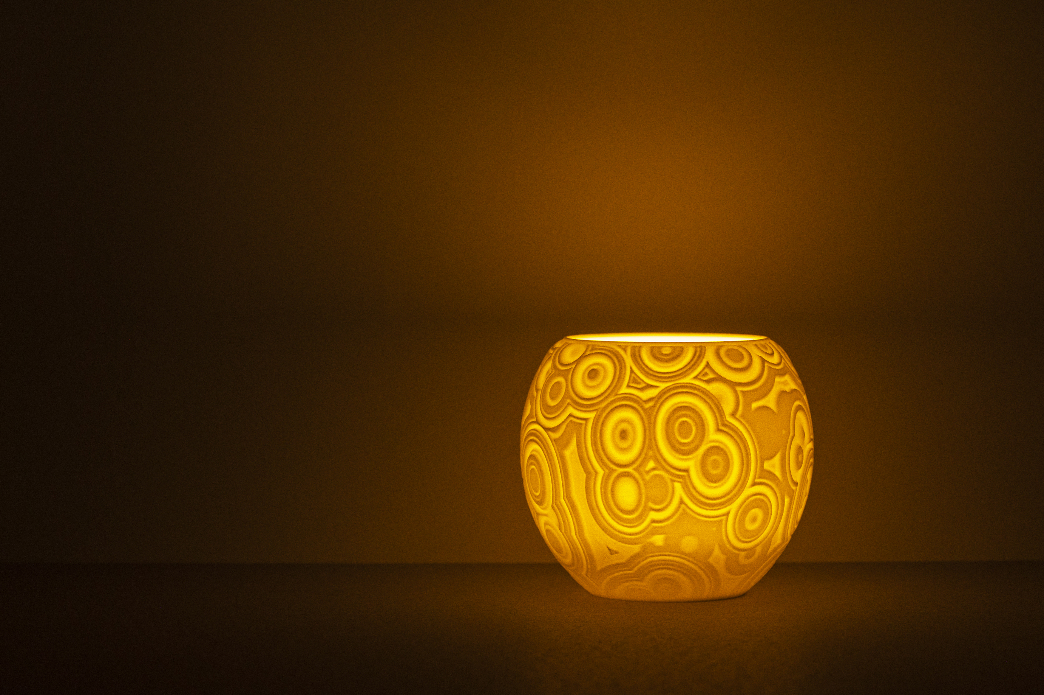 Decorative suggestion for Celestial Odyssey: Tealight holder with cosmic design. Perfect for stargazers and dreamers - variant Original (Elegant white), an original product by Cosmic Jubilee (1 of 3) - presented as a tealight, switched on.