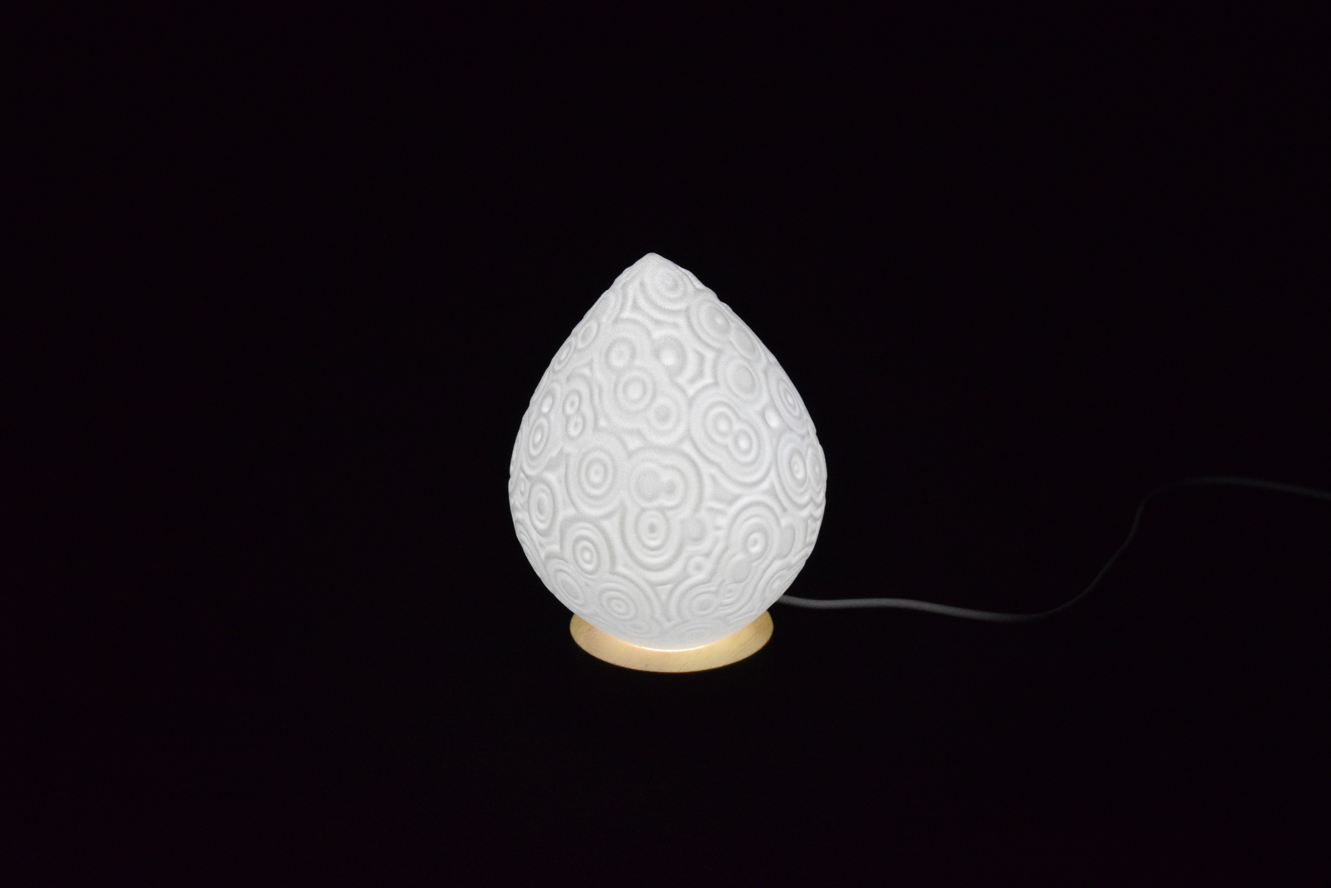 Decorative suggestion for Cosmic Drop: Desktop light with cosmic design. Encapsulates the beauty of the cosmos - variant Celestial Odyssey (Elegant white), an original product by Cosmic Jubilee (1 of 5) - presented as desktop, table, or freestanding light, switched on.