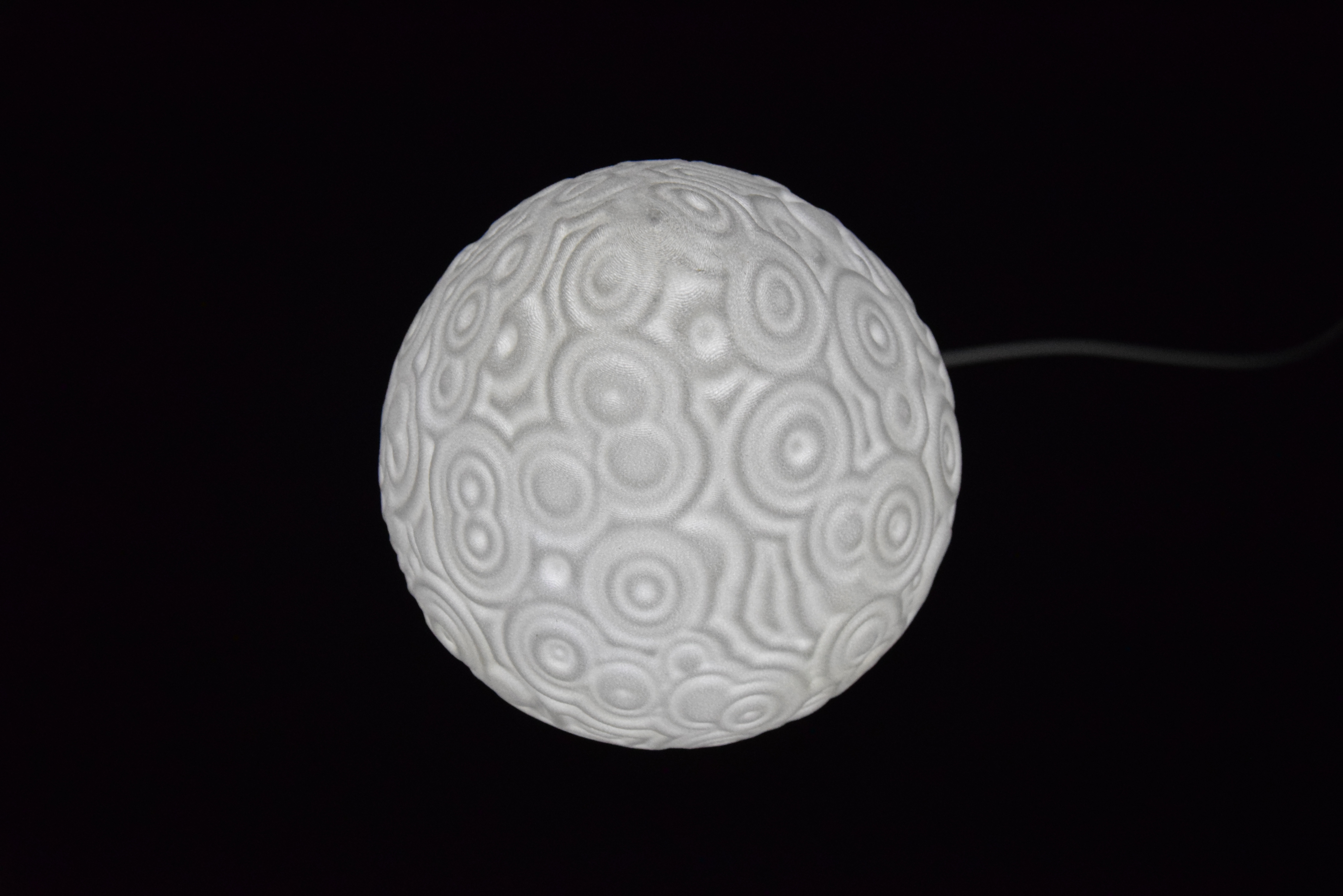 Decorative suggestion for Cosmic Drop: Desktop light with cosmic design. Encapsulates the beauty of the cosmos - variant Celestial Odyssey (Elegant white), an original product by Cosmic Jubilee (3 of 5) - presented as desktop, table, or freestanding light, switched on.