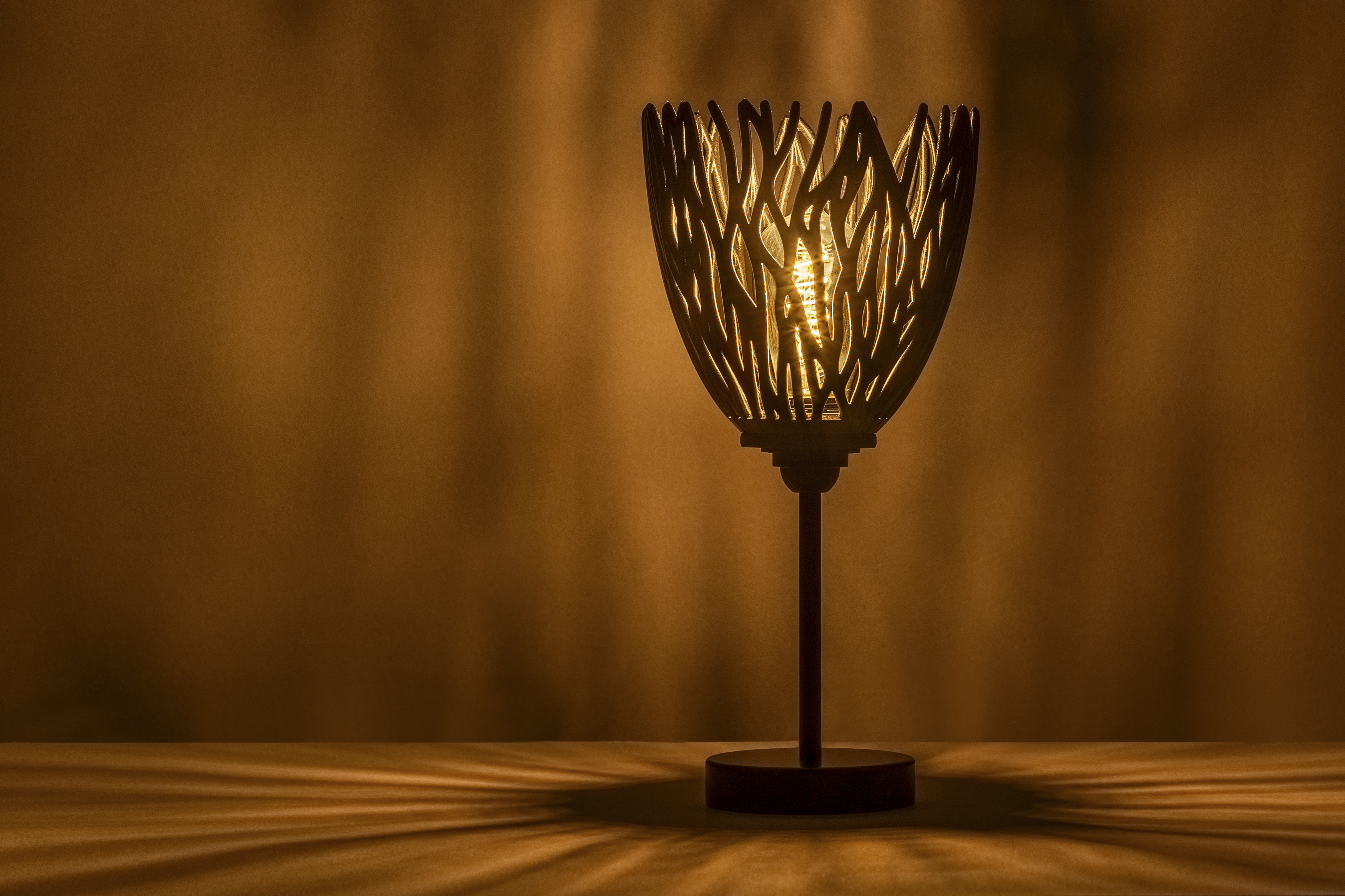 Decorative suggestion for Empyreal Bloom: Pendant lampshade with organic growth design. Mesmerizing shadow play for subtle elegance and ambiance - variant Original (Black with a hint of sparkle), an original product by Cosmic Jubilee (4 of 8) - presented as desktop, table, or freestanding light, switched on.