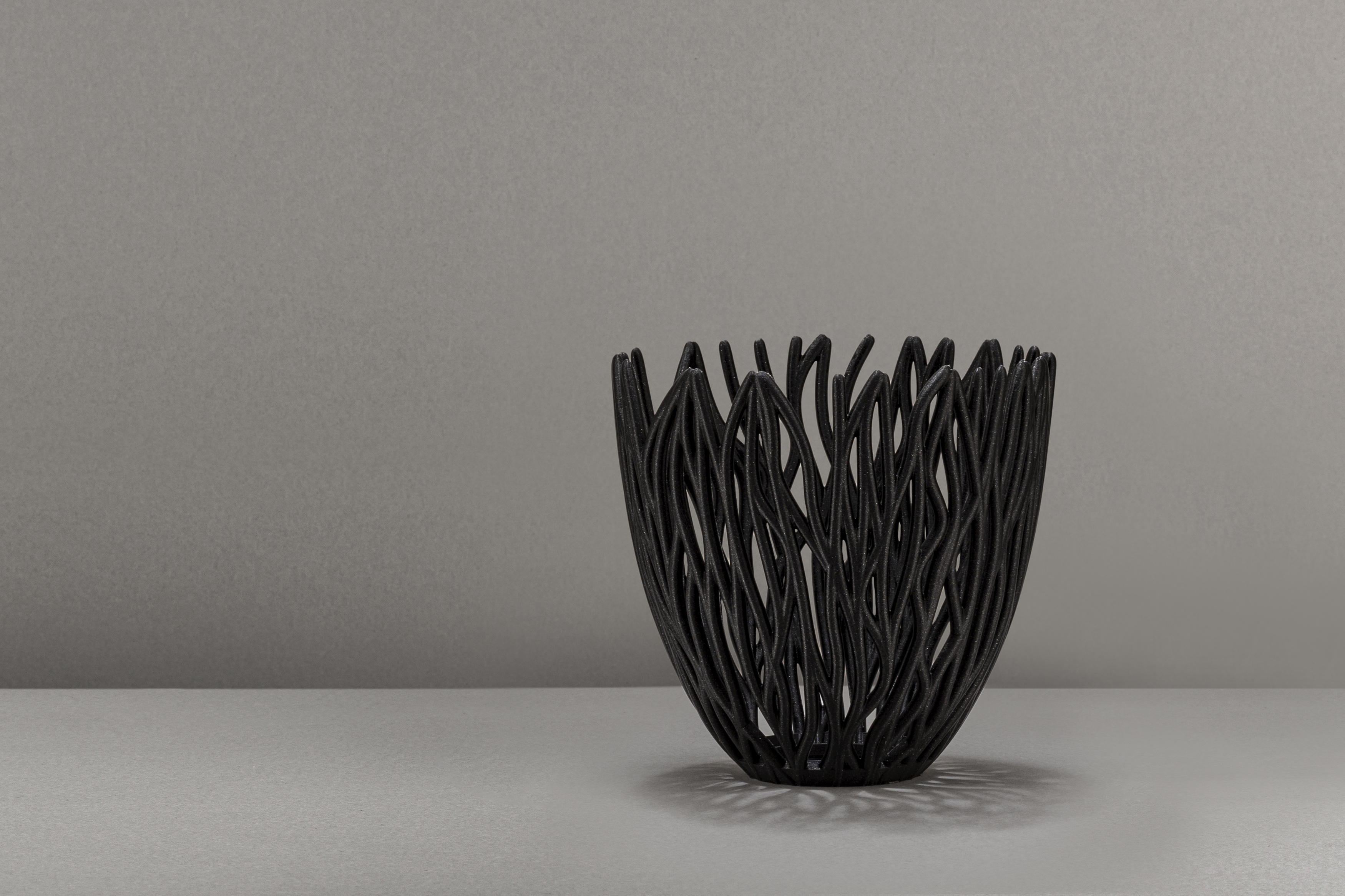 Decorative suggestion for Empyreal Bloom: Pendant lampshade with organic growth design. Mesmerizing shadow play for subtle elegance and ambiance - variant Original (Black with a hint of sparkle), an original product by Cosmic Jubilee (7 of 8) - presented as a decorative (non-water) vase or standalone showpiece.