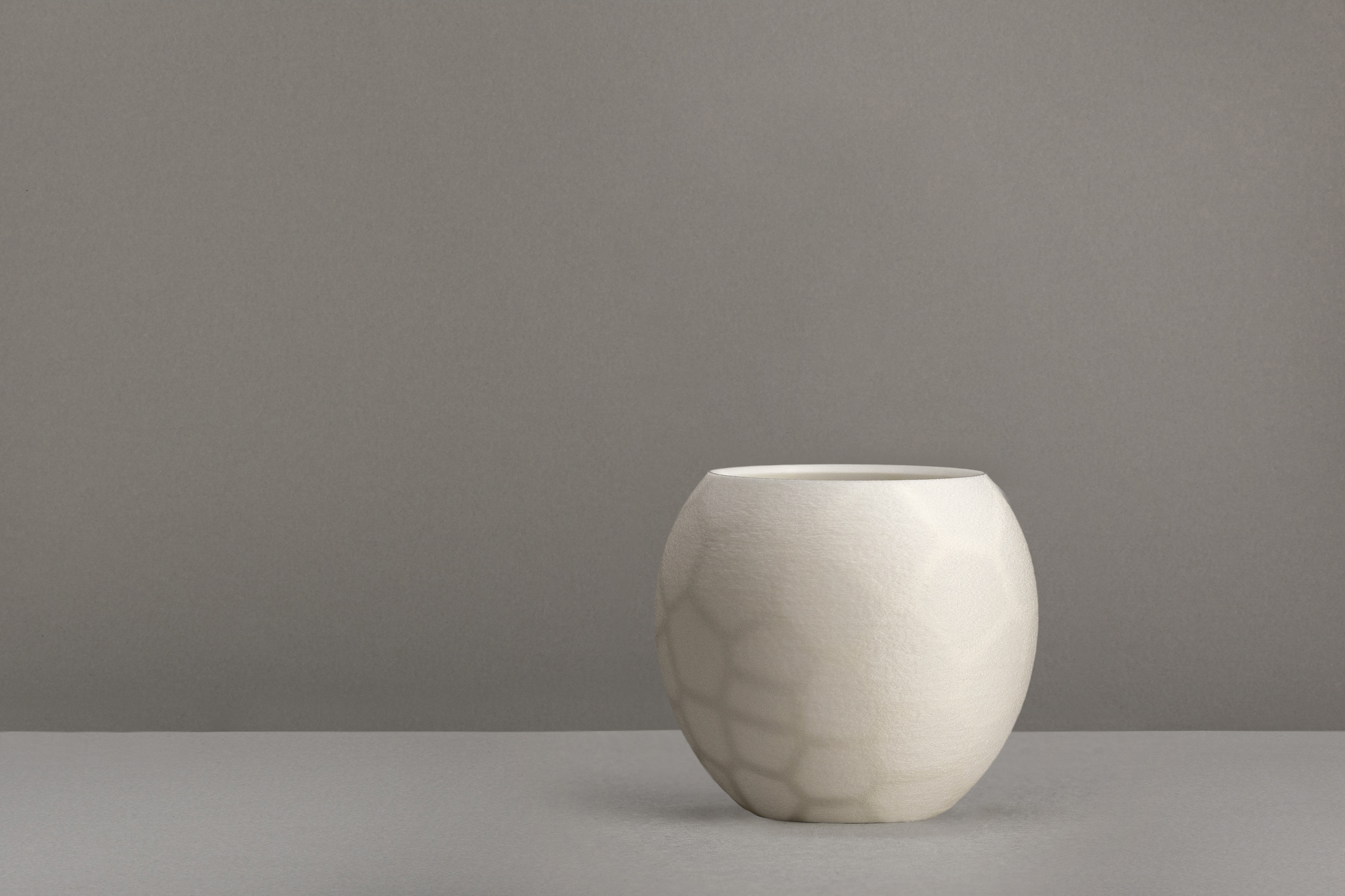 Decorative suggestion for Furtive Shroud: Tealight holder with a hidden organic pattern, revealed only when lit. Witness light transform the ordinary to exceptional - variant Original (Elegant white), an original product by Cosmic Jubilee (2 of 3) - presented as a tealight, switched off.