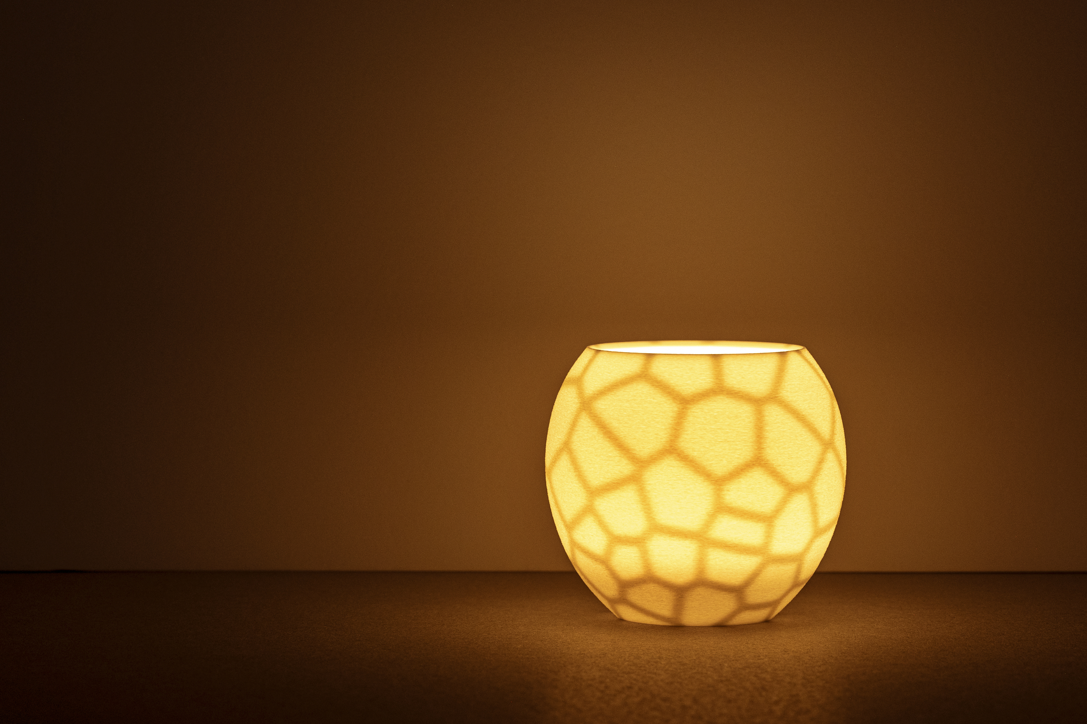 Decorative suggestion for Furtive Shroud: Tealight holder with a hidden organic pattern, revealed only when lit. Witness light transform the ordinary to exceptional - variant Original (Elegant white), an original product by Cosmic Jubilee (1 of 3) - presented as a tealight, switched on.