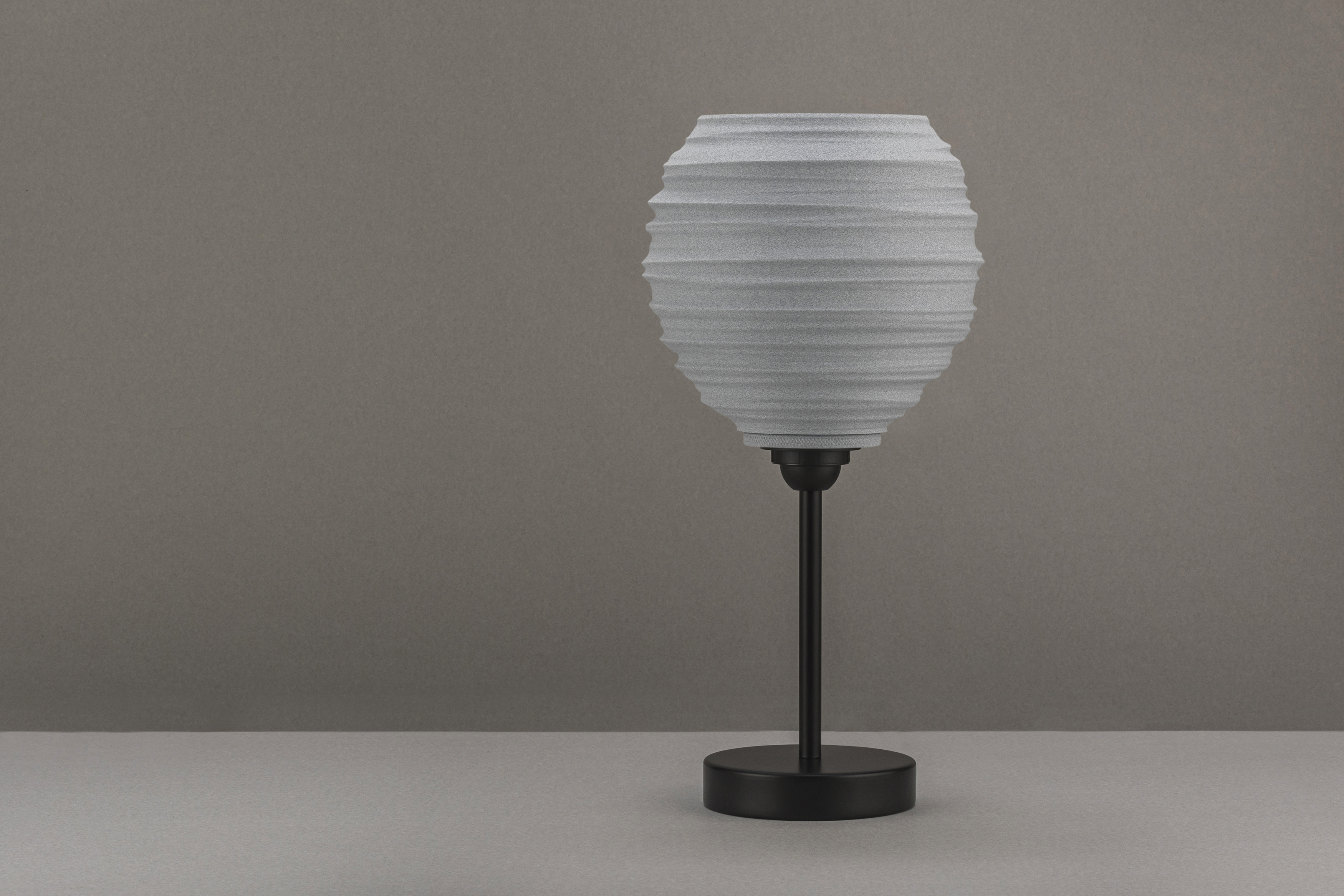 Decorative suggestion for Magma Shroud: Pendant lampshade mirroring tumultuous magma flow. Adds an elemental touch to modern decor - variant Granite Gray (Grainy textured stone gray spotlight), an original product by Cosmic Jubilee (4 of 6) - presented as desktop, table, or freestanding light, switched off.