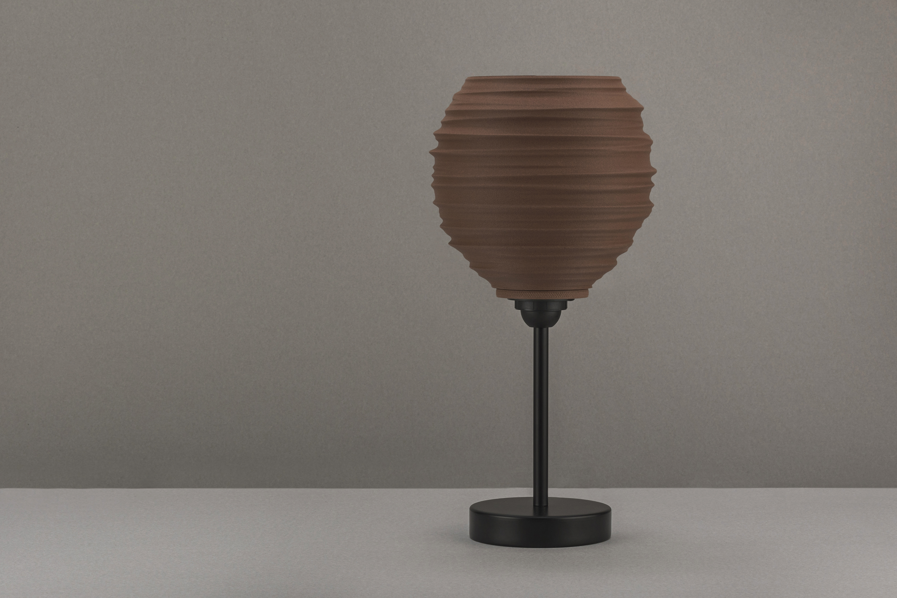 Decorative suggestion for Magma Shroud: Pendant lampshade mirroring tumultuous magma flow. Adds an elemental touch to modern decor - variant Stone Red (Grainy textured stone red spotlight), an original product by Cosmic Jubilee (4 of 6) - presented as desktop, table, or freestanding light, switched off.