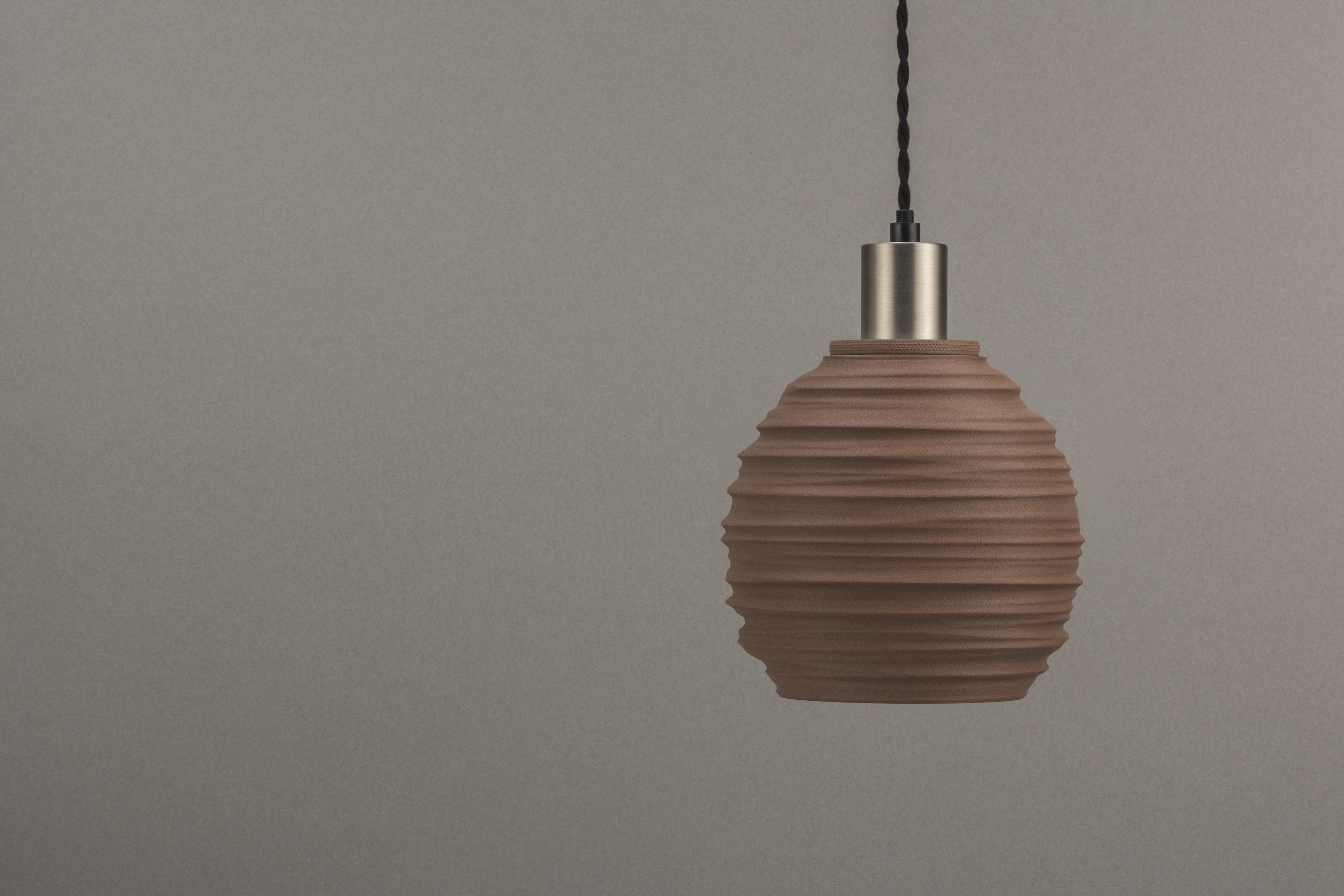 Decorative suggestion for Magma Shroud: Pendant lampshade mirroring tumultuous magma flow. Adds an elemental touch to modern decor - variant Stone Red (Grainy textured stone red spotlight), an original product by Cosmic Jubilee (2 of 6) - presented as pendant light, hanging from ceiling, switched off.