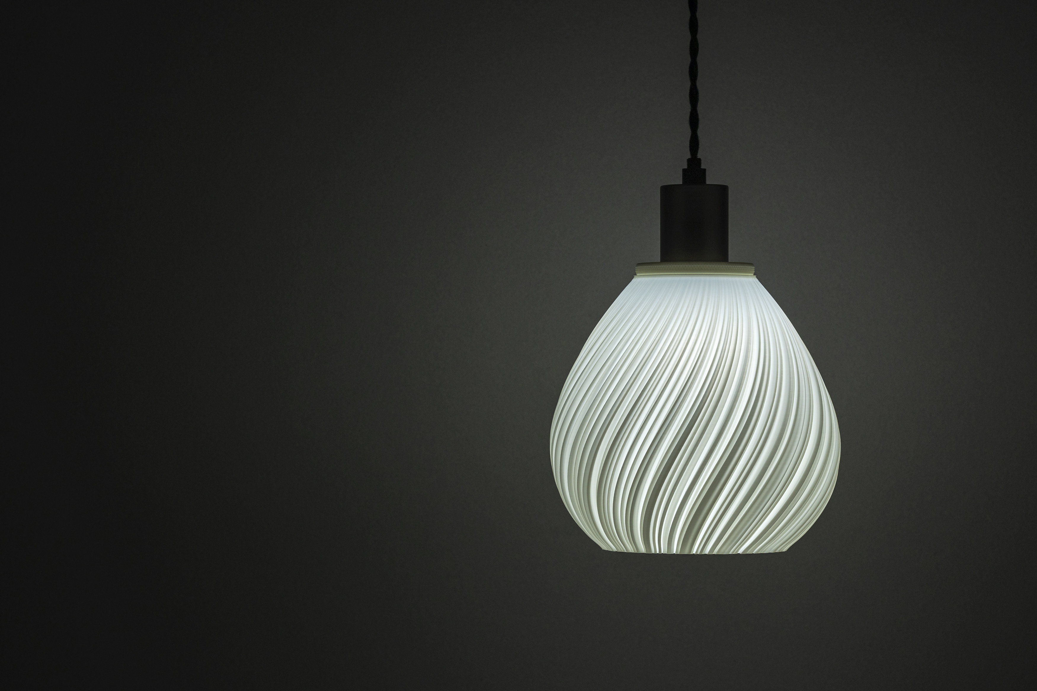 Decorative suggestion for Pellucid Sweep: Spiraling pleats pendant lampshade for a balletic light play. Transforms environments with mesmerizing beauty - variant Original (Milky white), an original product by Cosmic Jubilee (1 of 6) - presented as pendant light, hanging from ceiling, switched on.