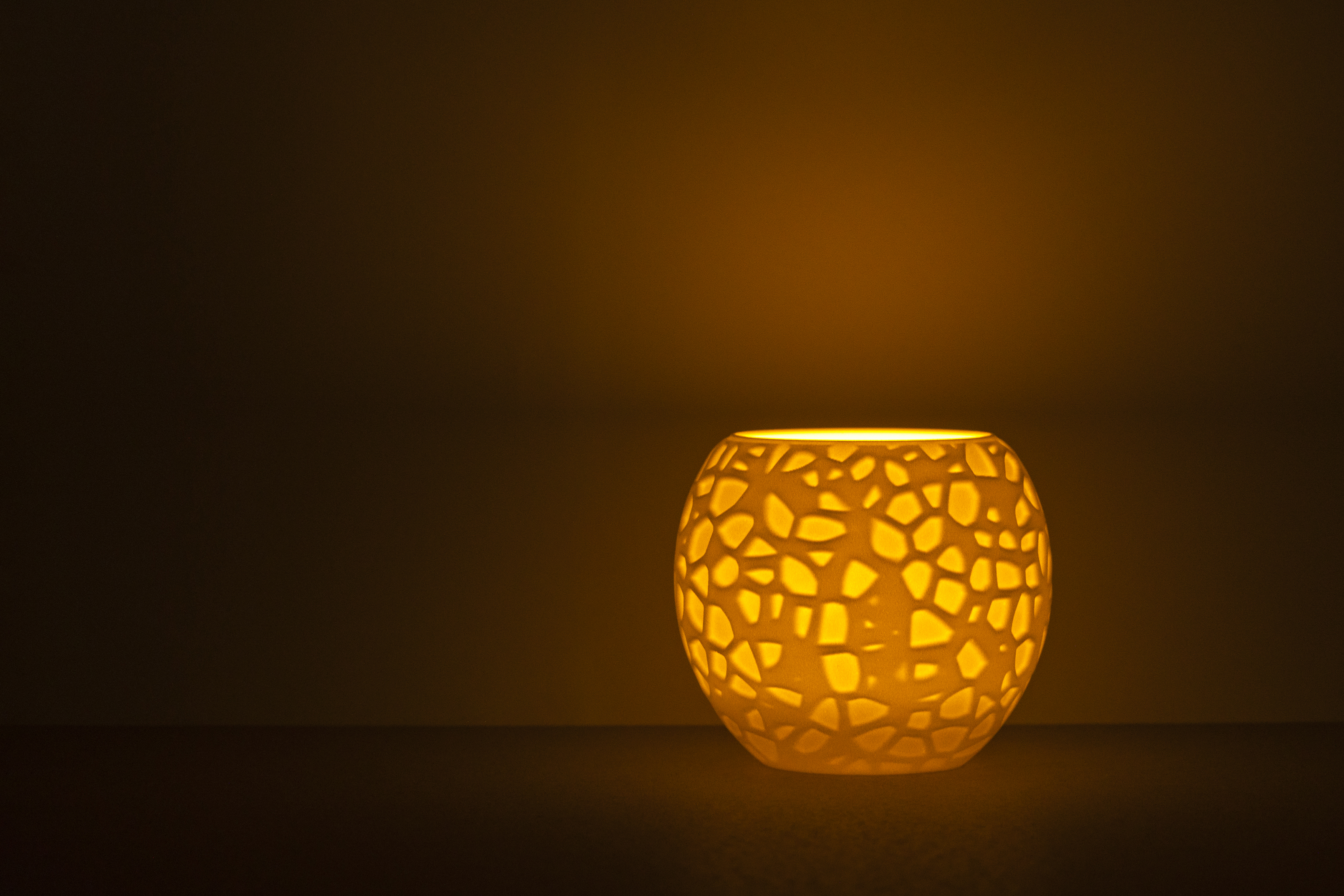 Decorative suggestion for Petrified Shallows: Voronoi pattern tealight holder echoing life's journeys. Warm glow casting memories and paths in light - variant Original (Elegant white), an original product by Cosmic Jubilee (1 of 3) - presented as a tealight, switched on.
