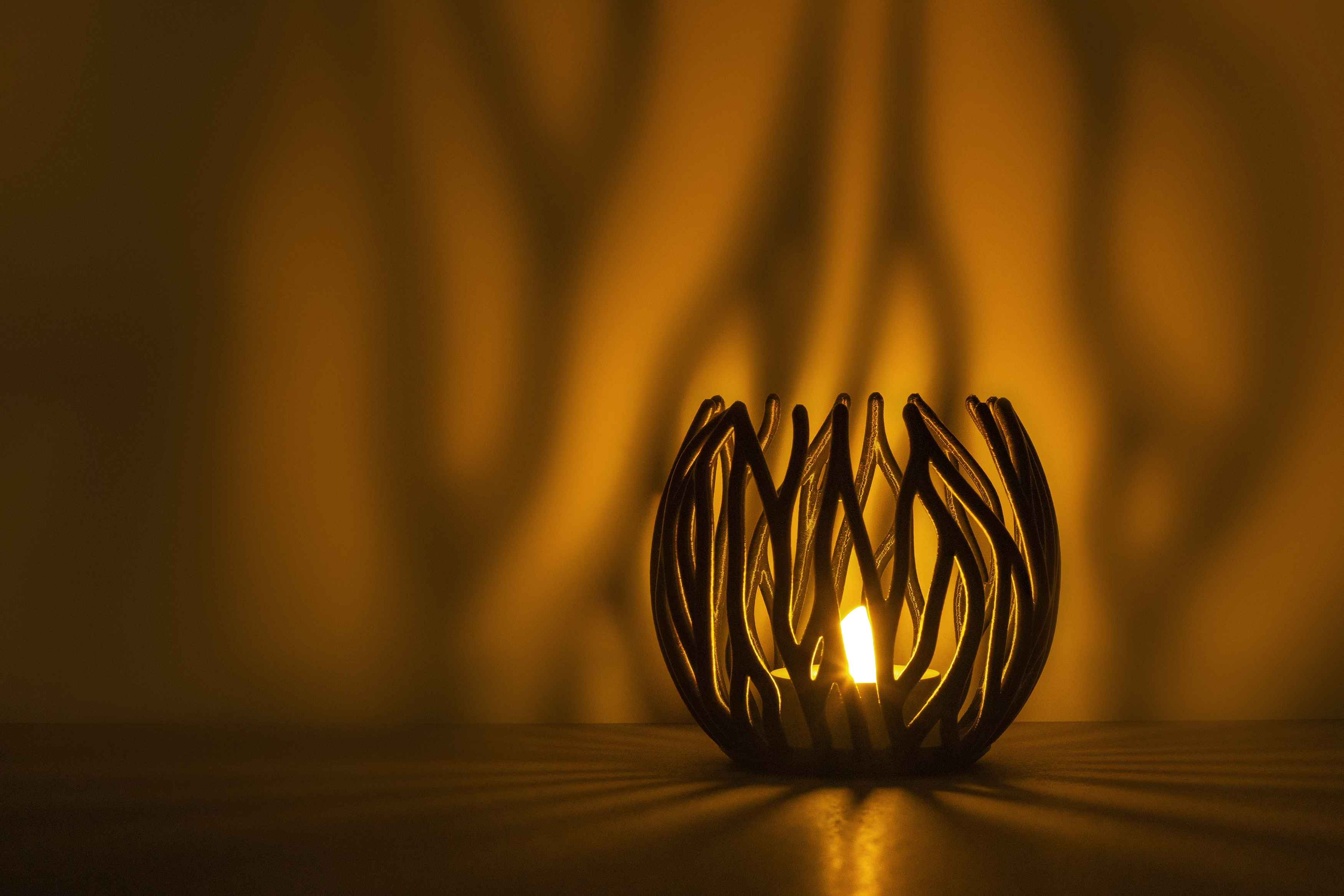 Decorative suggestion for Twinkling Bloom: Elegant tealight holder with organic, floral-inspired design. Mesmerizing shadow play for subtle elegance and ambiance - variant Oak (Changing deep greens and browns), an original product by Cosmic Jubilee (1 of 3) - presented as a tealight, switched on.