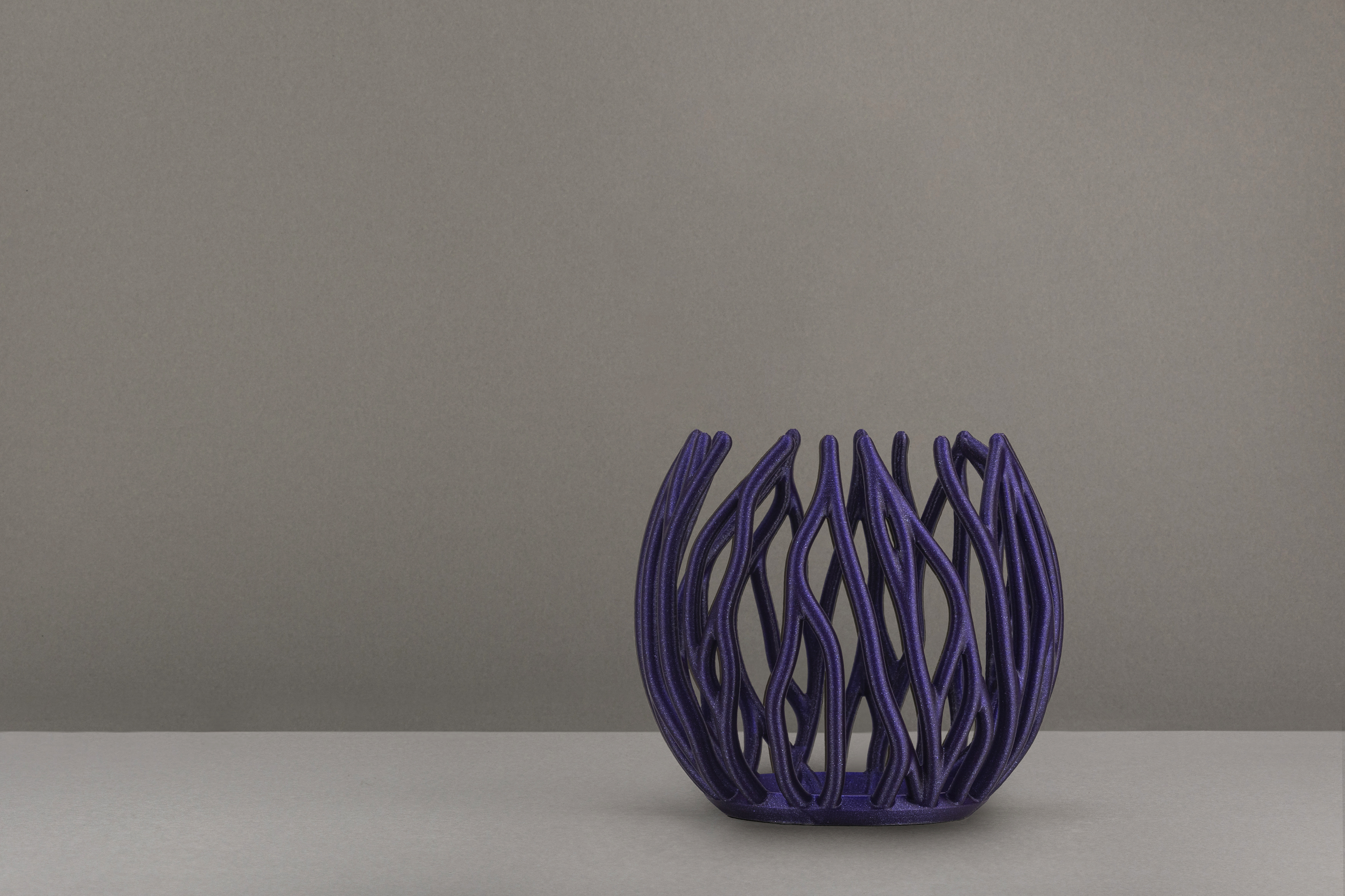 Decorative suggestion for Twinkling Bloom: Elegant tealight holder with organic, floral-inspired design. Mesmerizing shadow play for subtle elegance and ambiance - variant Plum (Fancy purple tones and shine), an original product by Cosmic Jubilee (2 of 3) - presented as a tealight, switched off.